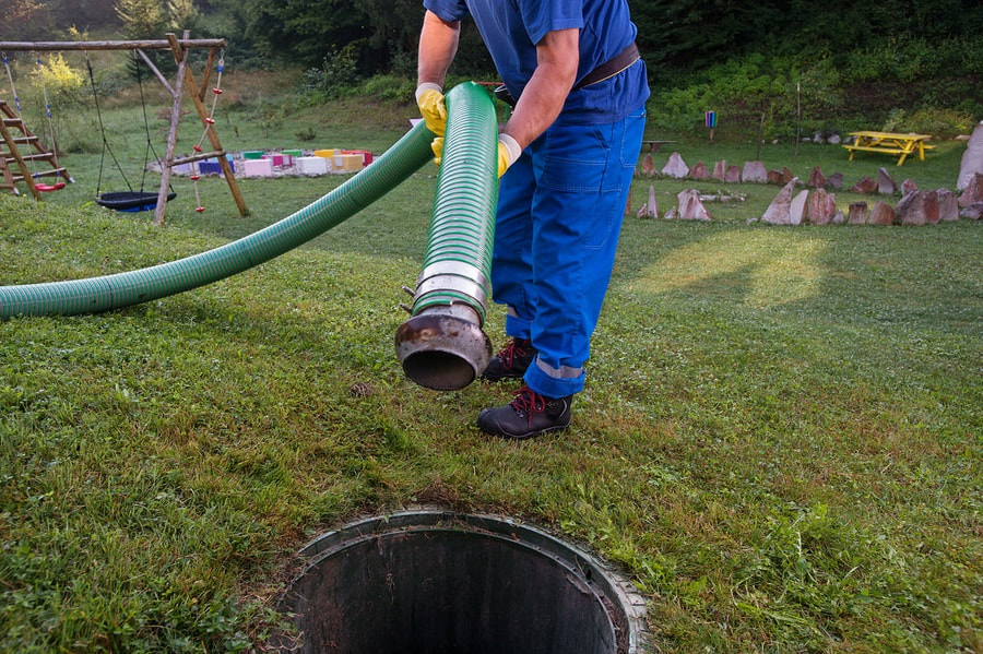 Worker inserting septic hose to pump tank